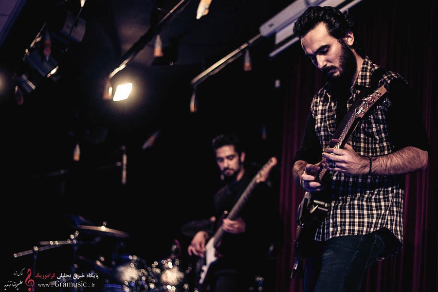 AndishiA on guitar with the drummer behind him